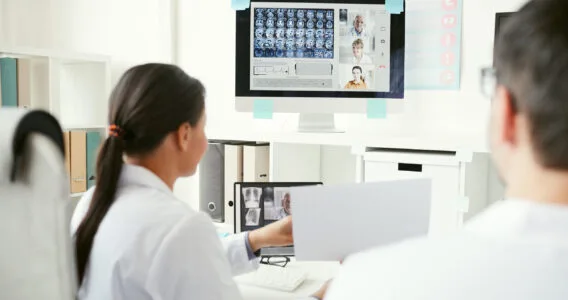 Deux professionnels de santé collaborant sur un projet numérique avec des données médicales affichées sur un écran.